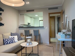 Un salon avec un canapé, des fauteuils, une table basse et un téléviseur.