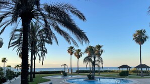 A pool area with palm trees, a clear sky, and a view of the sea. - Apartment 'Residencial Mar De Denia 2' with Sea View, Wi-Fi and Air Conditioning (Denia)