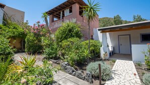 Una casa moderna con un sendero de piedra, un jardín exuberante y una terraza de madera.