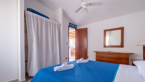 Una habitación de hotel con cama, cómoda de madera, espejo y ventilador de techo.