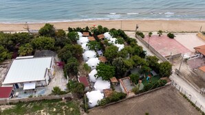 Vista aérea de una propiedad costera con varias estructuras esféricas, una playa y un área cercada con árboles.