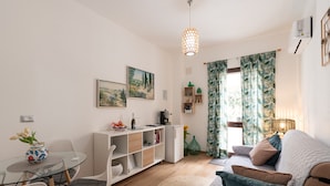 Uma sala de estar moderna com uma mesa de vidro, sofá branco e uma estante.