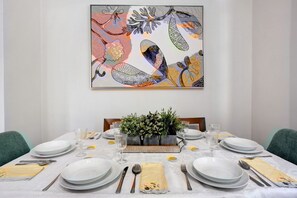 Une table à manger dressée avec des assiettes, des couverts et des verres, agrémentée d’une plante décorative en guise de centre de table.