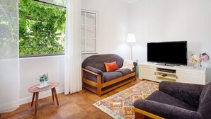 A living room with a sofa, TV, and a small table with a lamp.