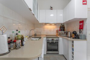A modern kitchen with white cabinets, a built-in oven, and a coffee machine. - A Minha Casa – Your Holiday Home in Funchal with Sea Views (Funchal)