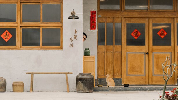 A traditional building with wooden doors, a bench, and a cat sitting outside. - TUNGWEI38 HOSTEL (Magong)