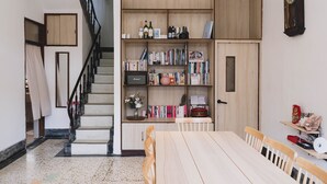 A cozy reading nook with a wooden bookshelf, a dining table, and a staircase. - TUNGWEI38 HOSTEL (Magong)
