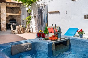 Un bain à remous avec une table, deux verres à vin et une bouteille de vin.