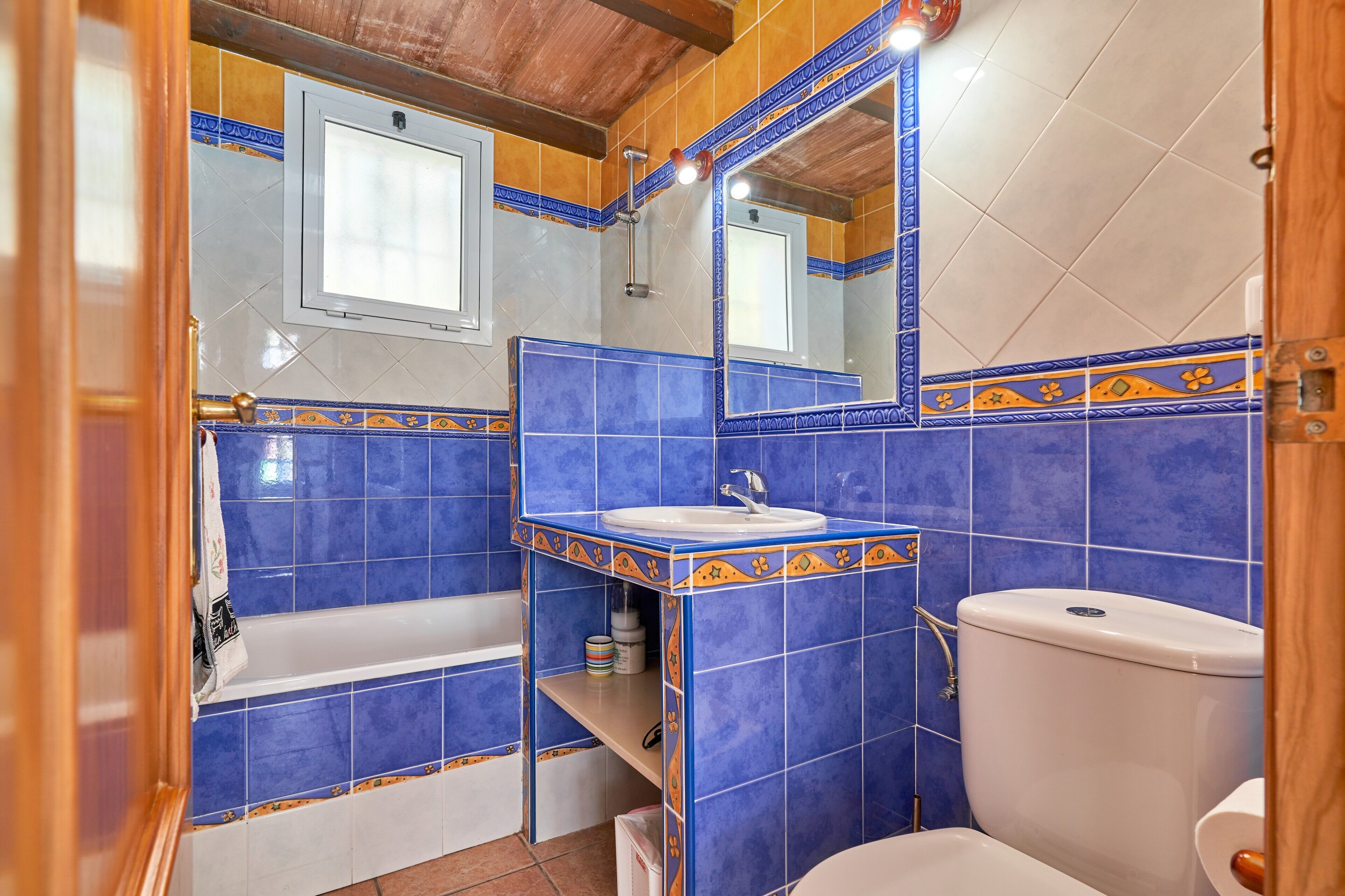 Un bagno con piastrelle blu, un lavandino bianco e un water.