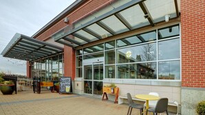 A café with outdoor seating, a glass enclosure, and a sign indicating it serves local beer.