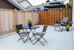 An outdoor patio with a table and chairs, a wooden fence, and potted plants.