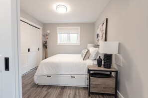 Une chambre à coucher avec un lit, une table de chevet, une lampe et une fenêtre.