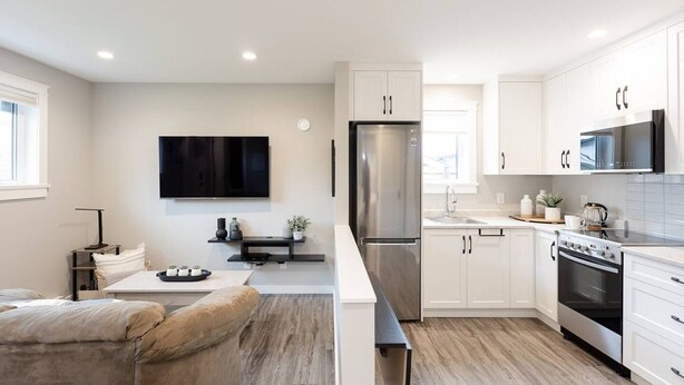 A modern kitchen with white cabinetry, a stainless steel refrigerator, a microwave, and an oven.