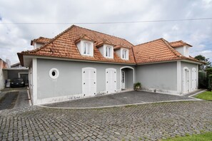 A two-story building with a tiled roof, a driveway, and a small garden area.