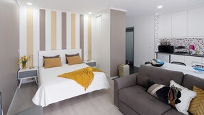 Una habitación de hotel moderna con una cama grande, un sofá, un escritorio y una kitchenette.