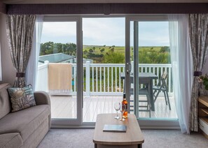 A room with a sliding glass door leading to an outdoor deck with a view of a green landscape.