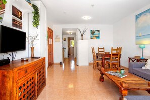A spacious living area with a wooden coffee table, a TV, and a dining set.