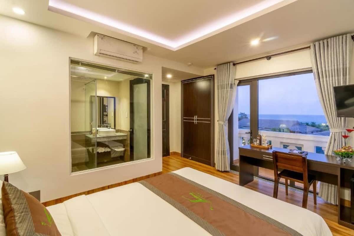 Ein Hotelzimmer mit Bett, Schreibtisch, Stuhl, Fernseher, Kleiderschrank und einem großen Fenster mit Blick.