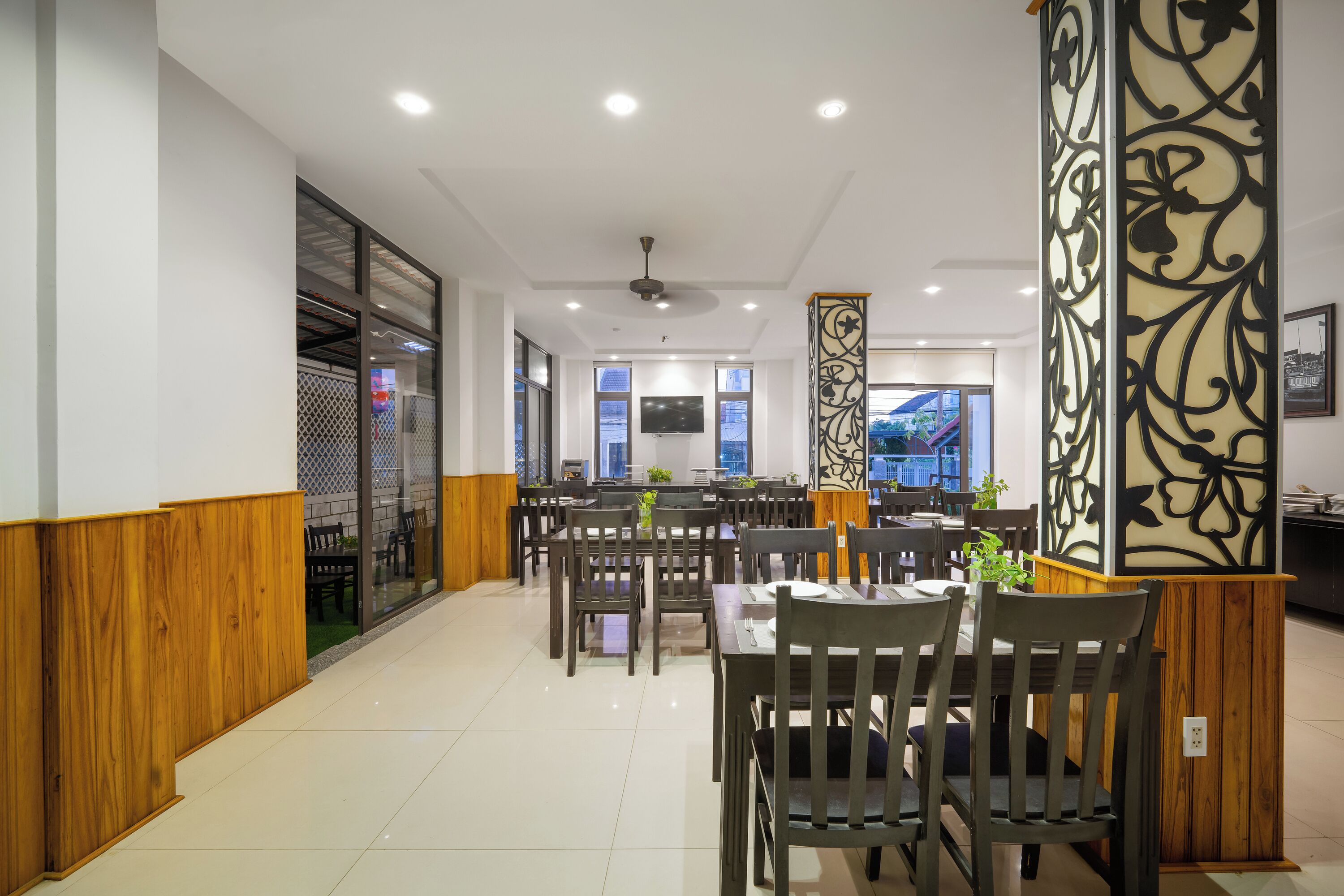 Un restaurante con paneles de madera, un ventilador de techo y un televisor colgado en la pared.