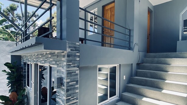 A modern two-story house with a stone exterior, a wooden door, and a staircase leading to the upper level.