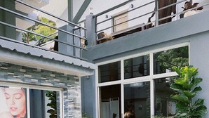 A modern building with large windows, outdoor seating, and potted plants.