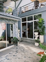 A modern building with large windows, outdoor seating, and potted plants.