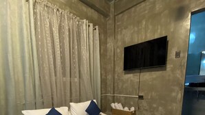 A bedroom with a large bed, a flat-screen TV mounted on the wall, and a wicker basket on the nightstand.