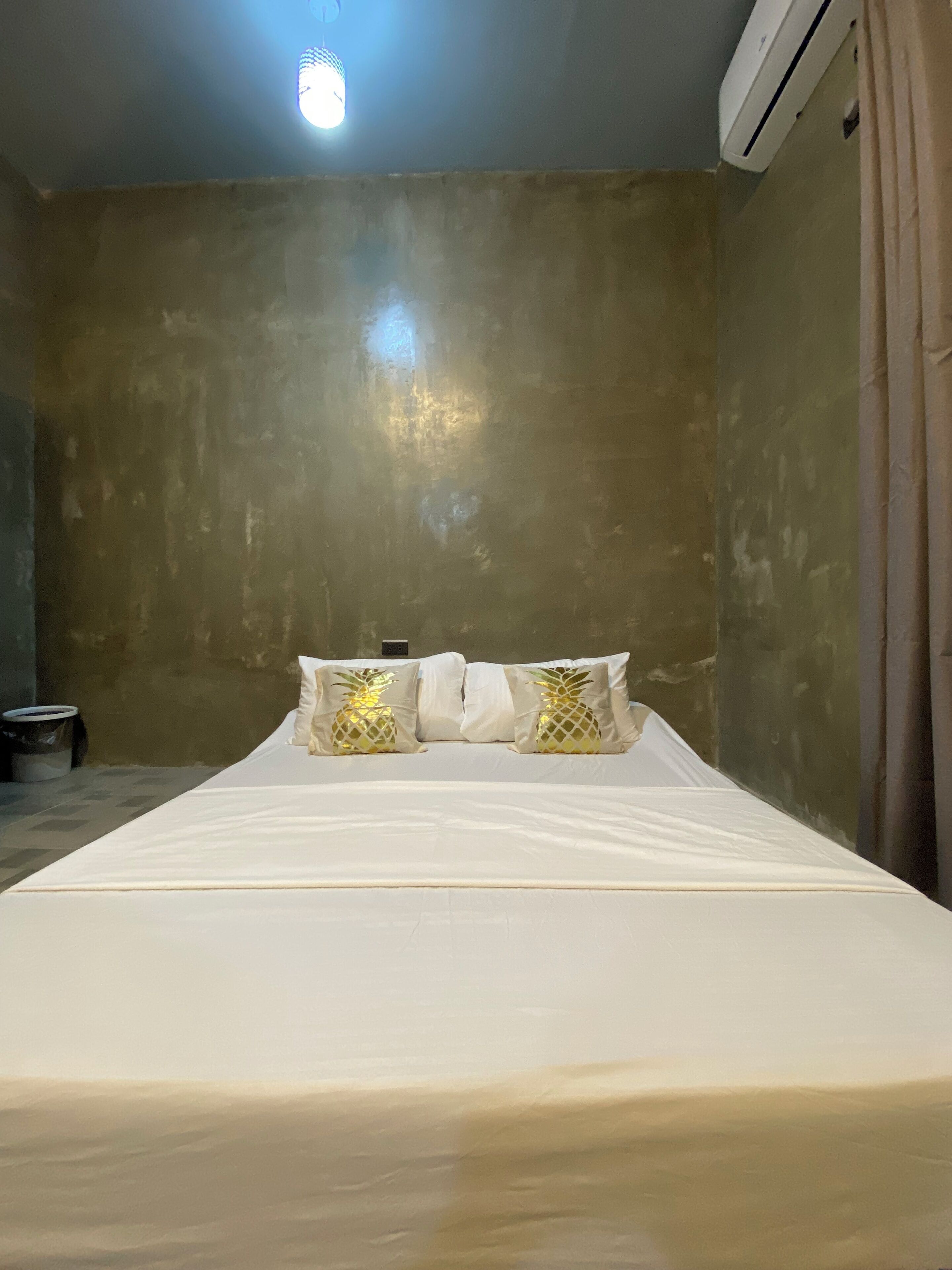 A room with a single bed, white bedding, and pineapple-patterned pillows.