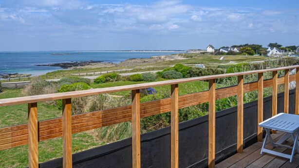 Eine Holzdar Terrasse mit Blick auf das Meer und eine grüne Landschaft.