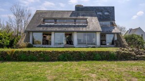 Ein modernes Haus mit einem geneigten Dach, großen Fenstern und einem Steinfundament.