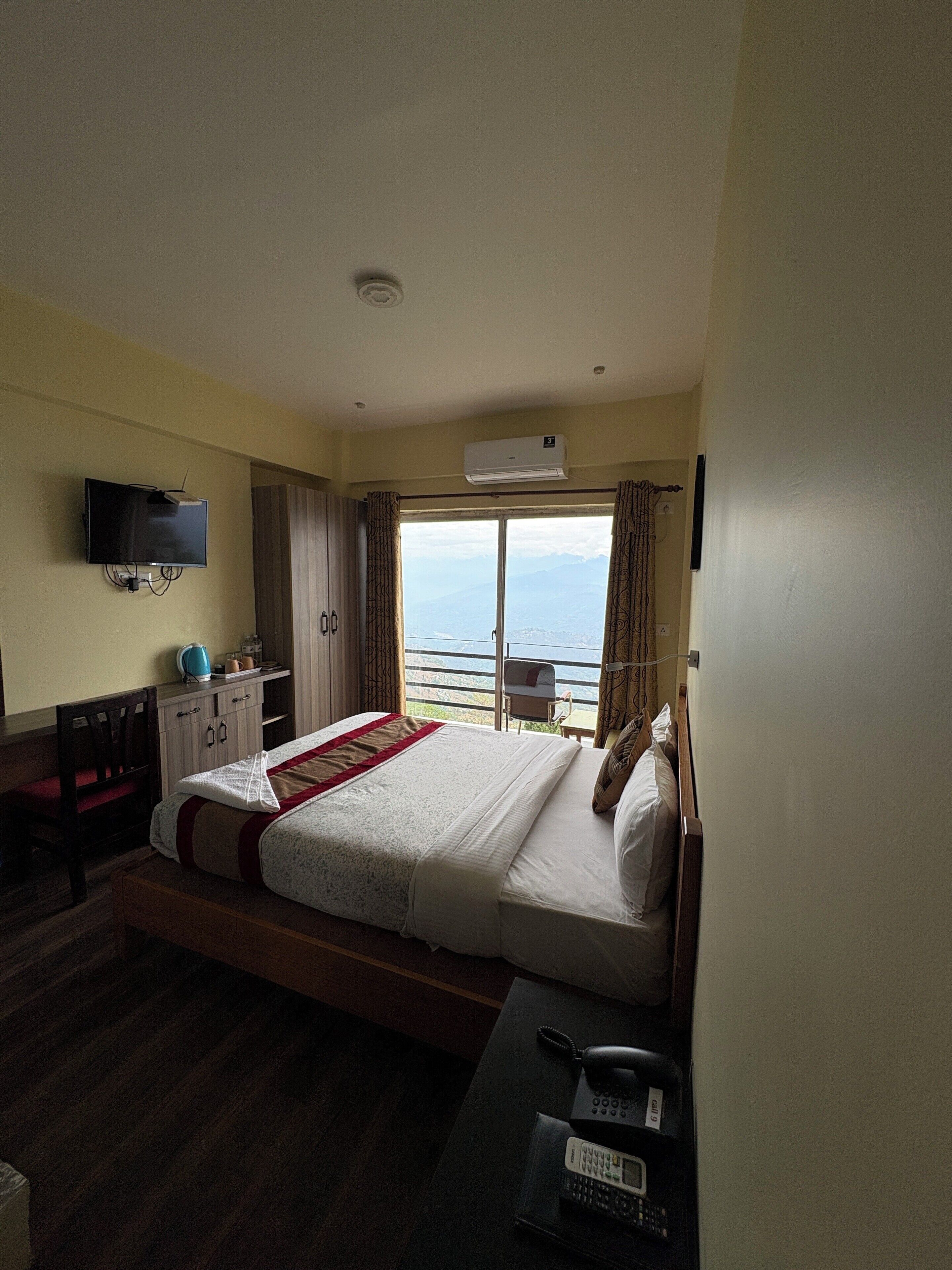 Une chambre d’hôtel équipée d’un lit, d’un bureau, d’une chaise, d’une télévision, d’un climatiseur et offrant une vue sur la mer.