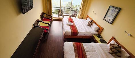 A hotel room with two beds, a desk, a chair, and a window with a view.