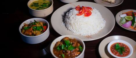 A variety of dishes including rice, curry, and vegetables on a dark wooden table.