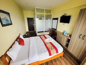 A bedroom with a bed, a wardrobe, a desk with a chair, a television, and a window. - HOTEL GREEN VALLEY  (Baluwapati Deupur)