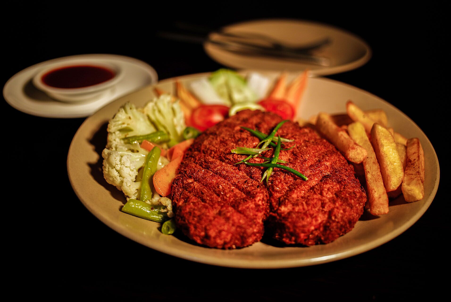 Een bord met een hamburger, groenten en friet.