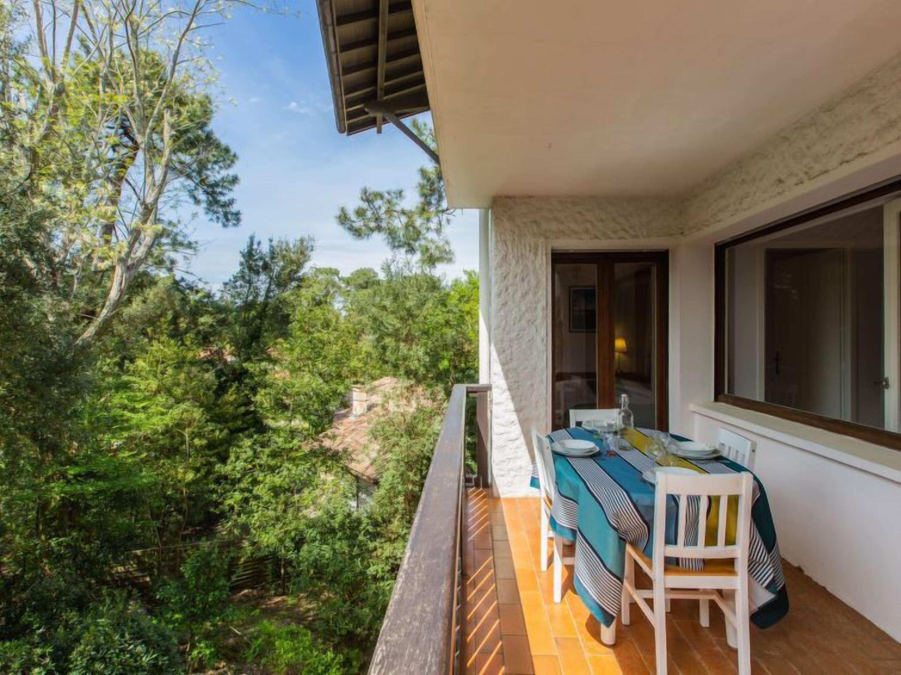 Un balcon avec une table et des chaises, donnant sur un paysage verdoyant et luxuriant.