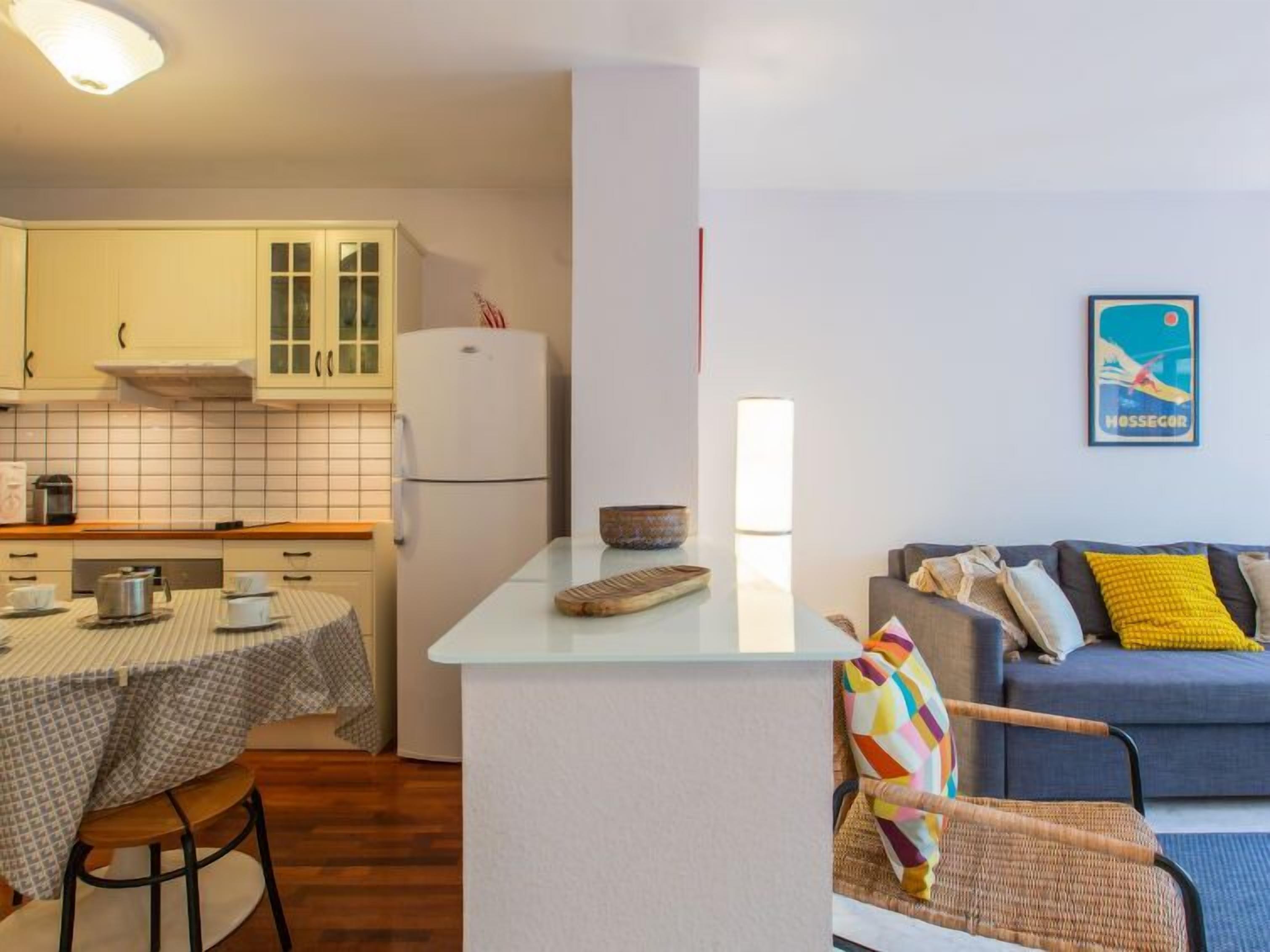 A compact kitchen with a dining table, a sofa, and a chair.