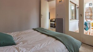 A bedroom with a bed, a door leading to a balcony, and a view of the outside. - Le Bourret by Interhome (Hossegor)