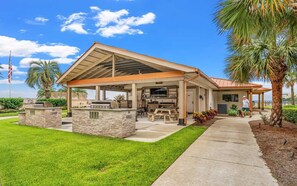 A modern house with a covered patio, outdoor kitchen, and a well-maintained lawn.