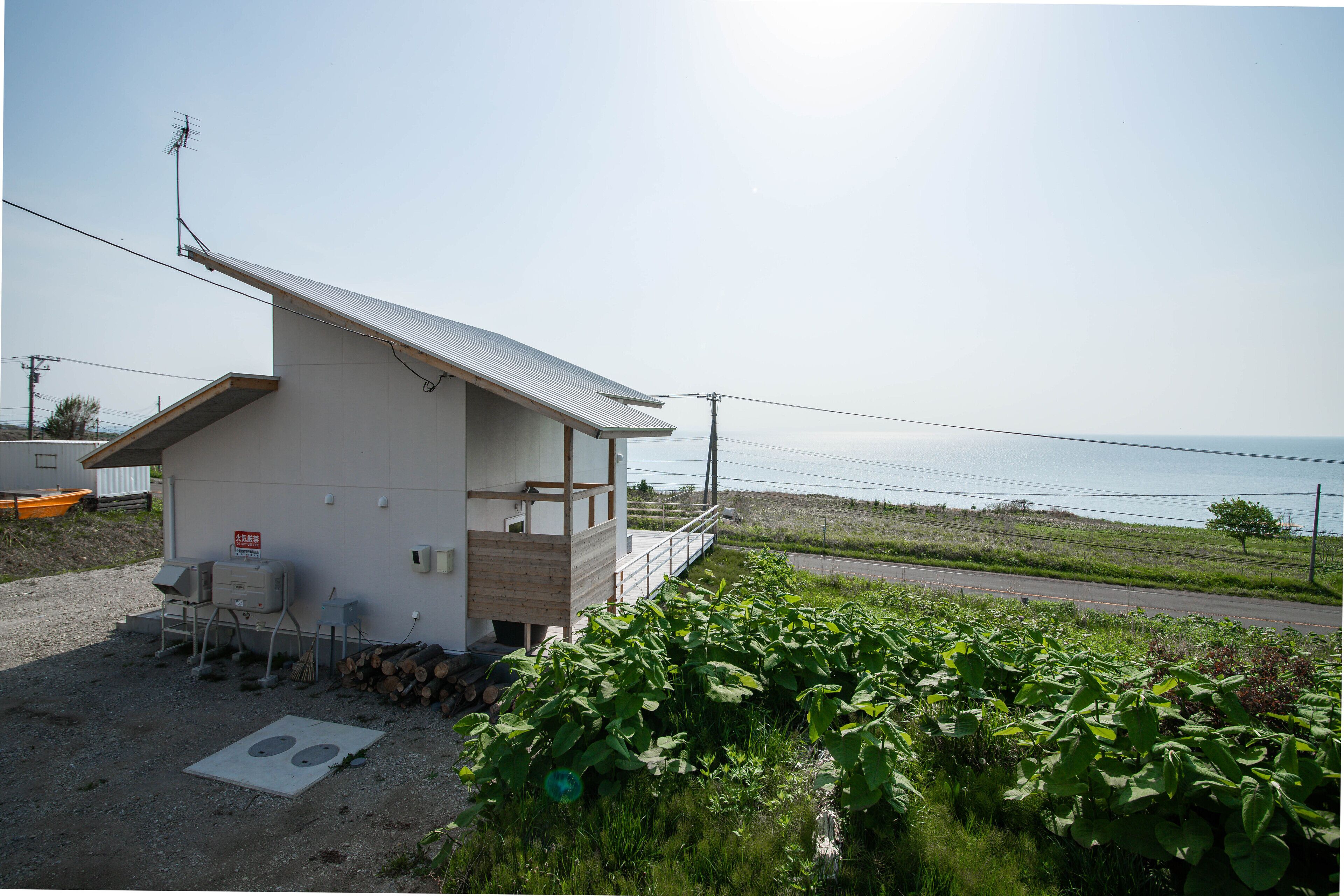 A small, single-story building with a sloped roof, a small porch, and a view of the sea.