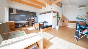 A spacious living area with wooden beams, a kitchen, and a dining area. - SUNNY SIDE HOUSE (Ishikari)