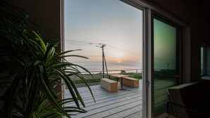 A balcony with wooden flooring, two wooden benches, and a potted plant. - SUNNY SIDE HOUSE (Ishikari)