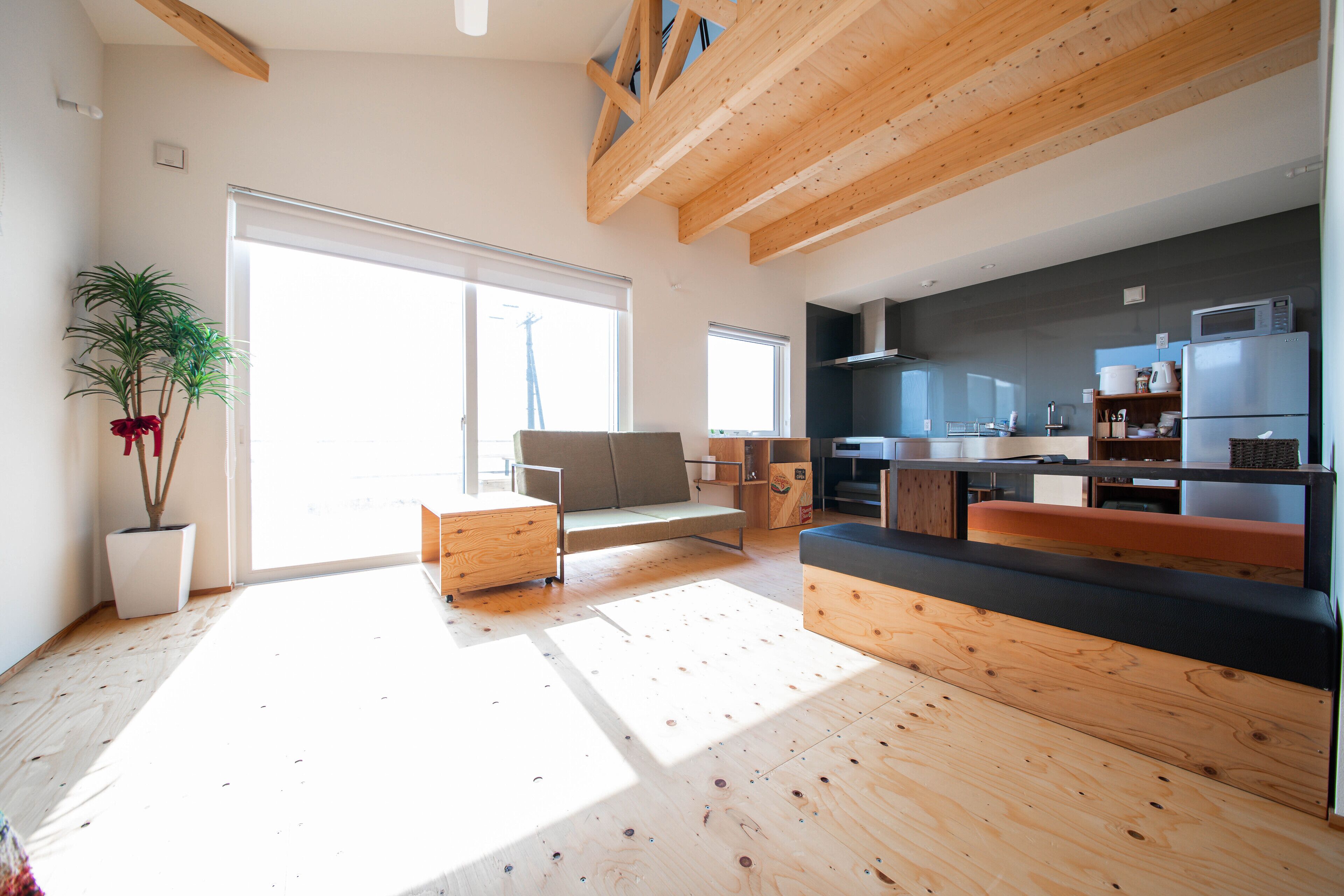 Una cocina moderna con vigas de madera, un comedor con un banco y un ventanal que proporciona luz natural.
