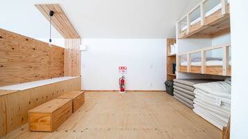 A room with wooden walls and floors, a fire extinguisher, and bunk beds with mattresses.