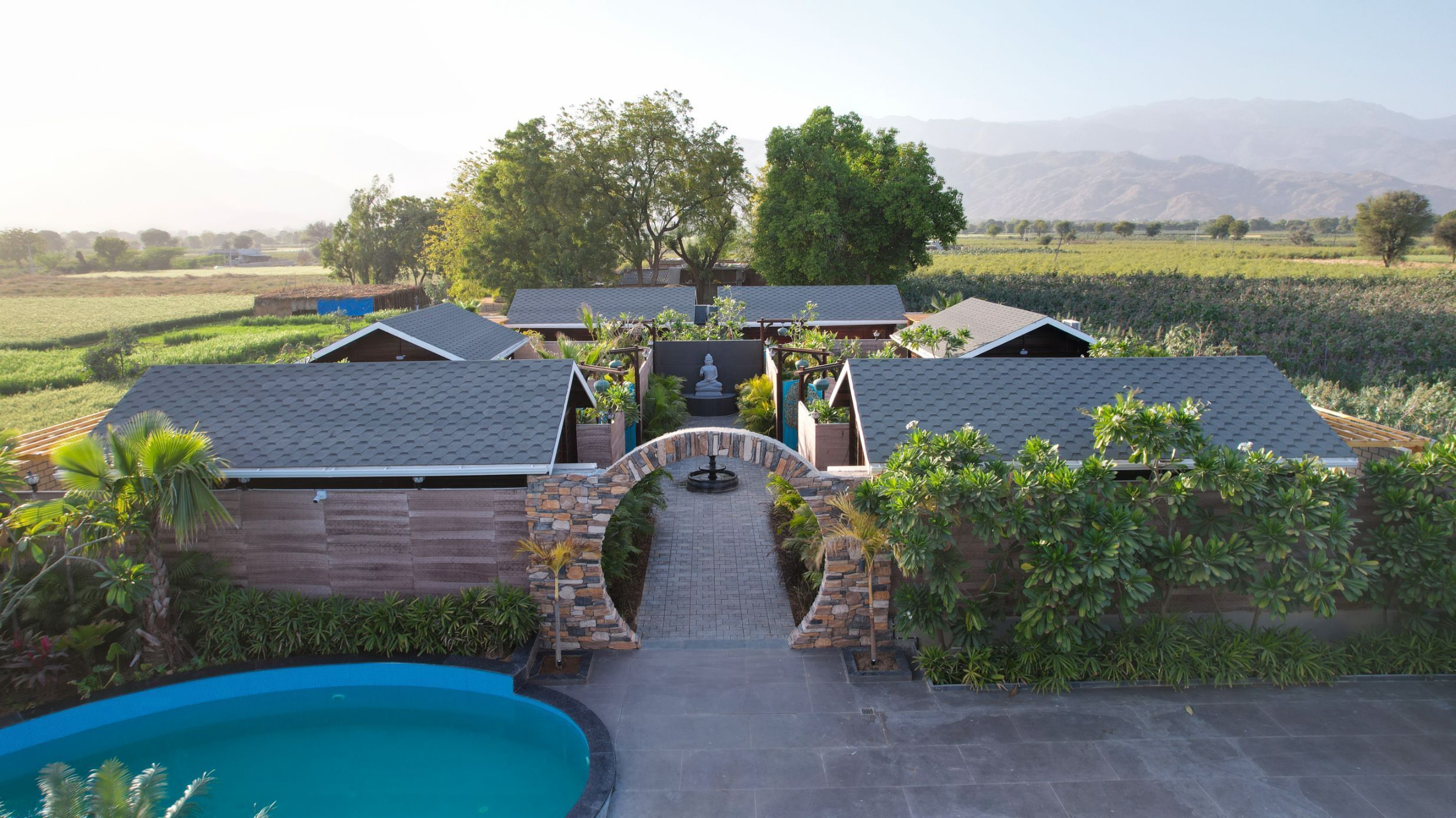 A residential property with a swimming pool, stone archway, and a view of the surrounding landscape.