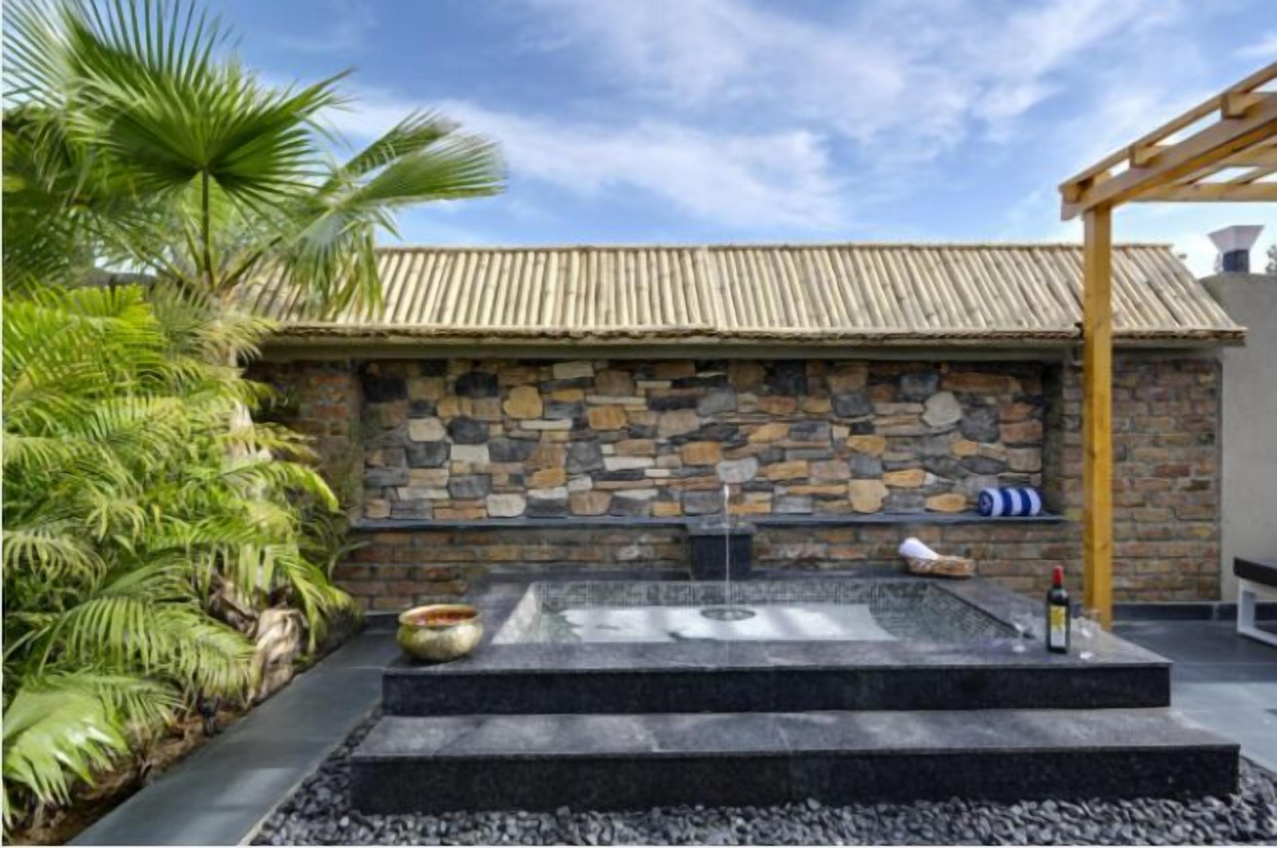 Mural de pedra com um elemento de água integrado e uma estrutura de pérgola.