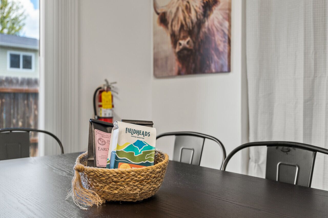 Una mesa de comedor con una cesta tejida que contiene paquetes de café y un extintor colgado en la pared.