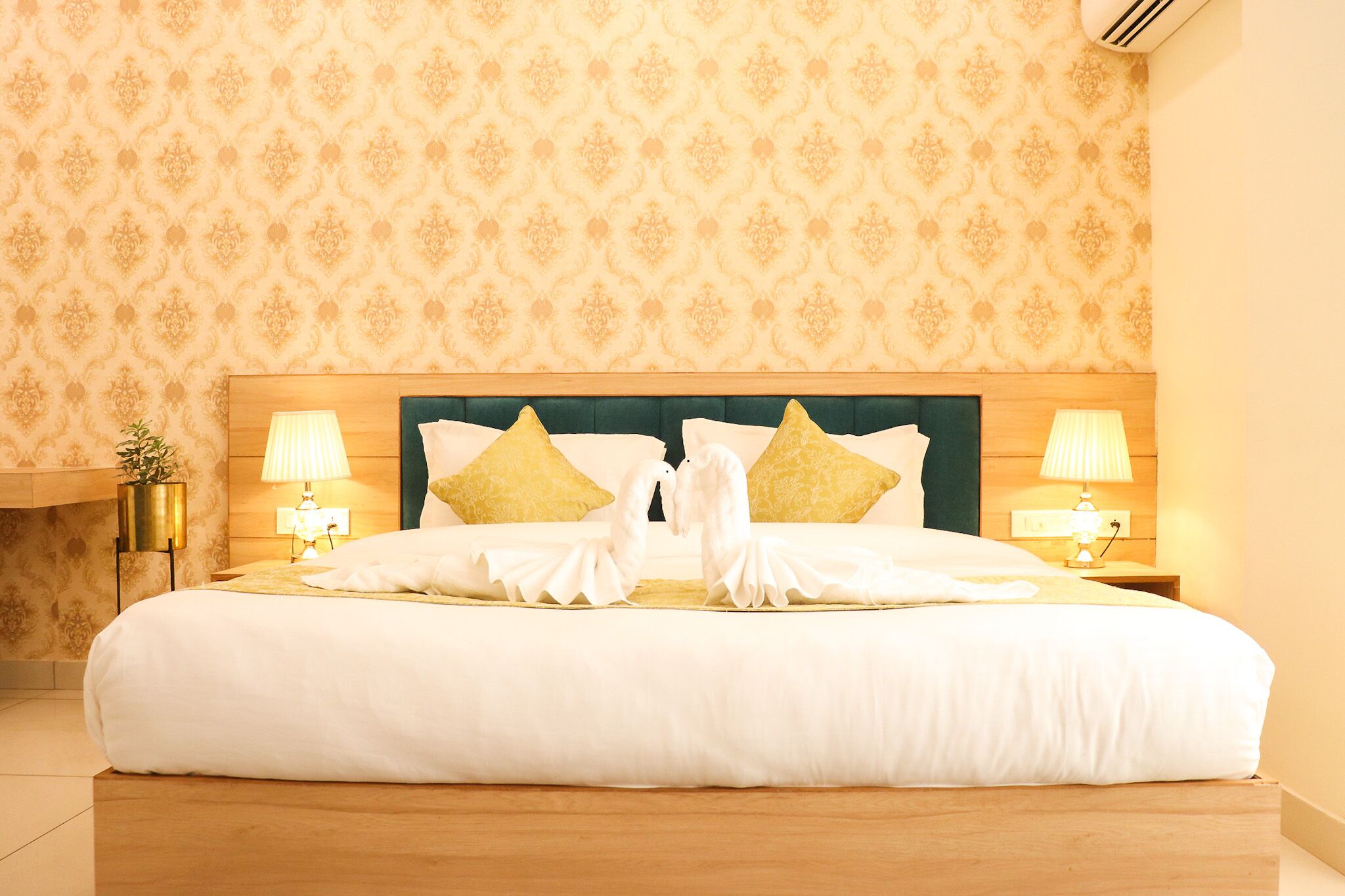 A neatly made bed with white linens and decorative pillows, two bedside lamps, and a wooden headboard.
