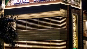 El exterior del Hotel Royal Palm, con un cartel llamativo que dice 'HOTEL' y señalización que indica 'ROYAL PALM'.