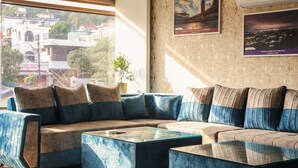 Una sala de estar moderna con un amplio sofá modular, una mesa de centro de vidrio y vistas a la ciudad a través de grandes ventanales.